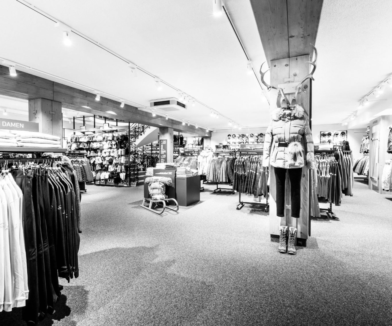 Eingangsbereich SPORT HUBER Innenansicht eines Bekleidungsgeschäfts mit Regalen und Mannequins.